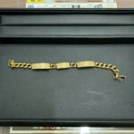 黒いトレーの上に置かれたK18のダイヤブレスレット。プレートと喜平チェーンが連なったデザインで、金色の輝きがはっきり見える。