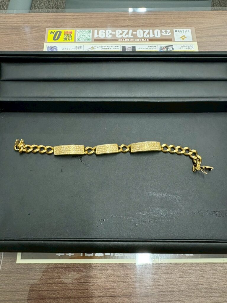 黒いトレーの上に置かれたK18のダイヤブレスレット。プレートと喜平チェーンが連なったデザインで、金色の輝きがはっきり見える。