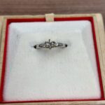 「蒔田店で査定した3石ダイヤリング。白いリングケースに置かれたシンプルなプラチナ系デザインのダイヤリングの写真。」